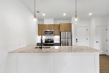 A kitchen with a marble countertop and white cabinets.
